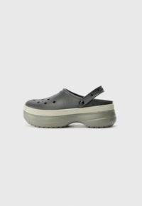 Black clogs with a raised sole and grey accents, featuring holes for ventilation, a back strap, and a textured rubber outsole.
