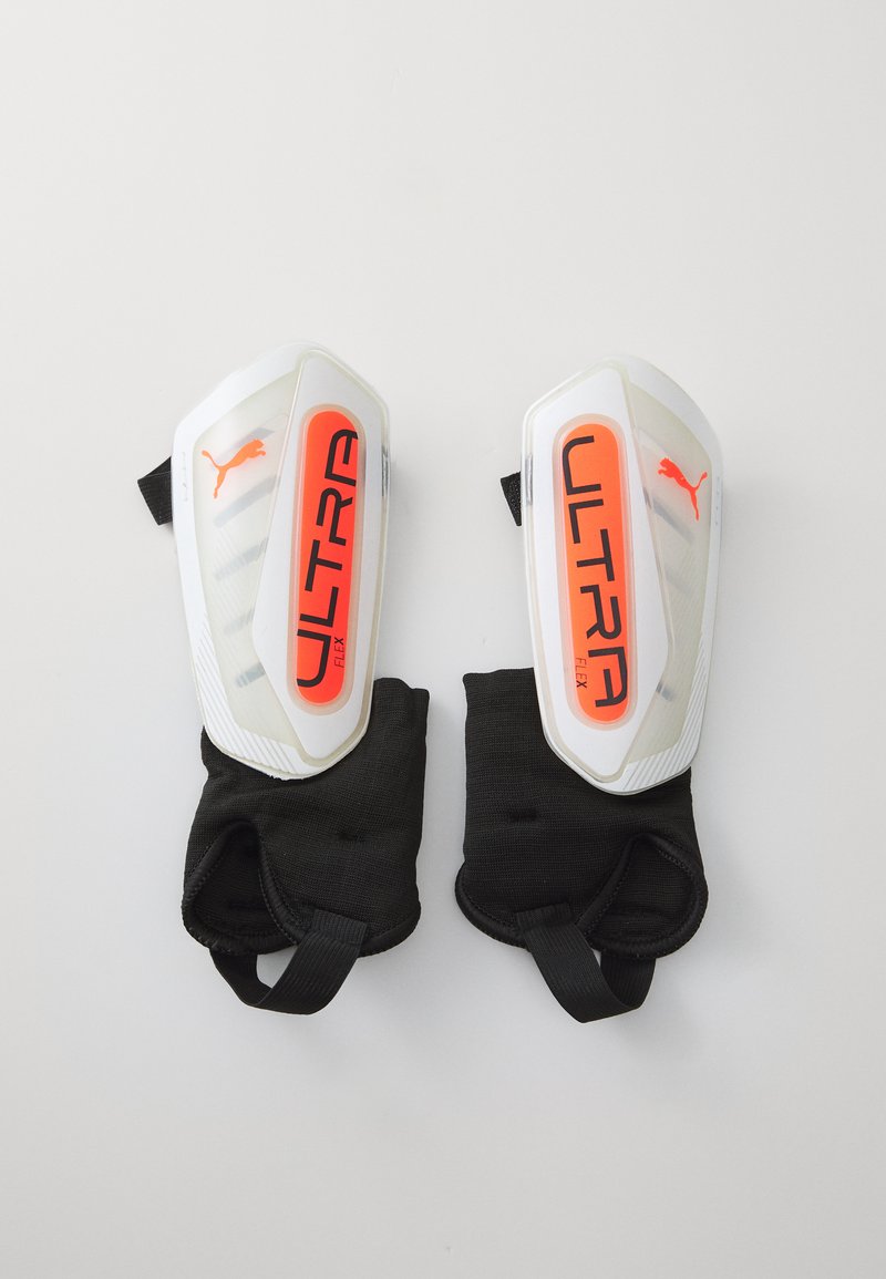 Puma Ultra Flex Schienbeinschoner mit glänzend weißer Außenschicht, leuchtend orangefarbenem Schriftzug, schwarzen Stoffärmel und verstellbaren Riemen für einen sicheren Sitz.