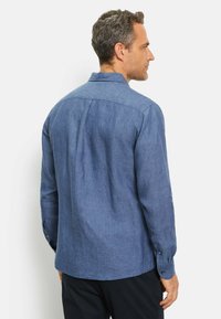  lichtblauwe, langemouwen shirt gemaakt van textuurstof, met een puntkraag en knoopmanchetten, gezien vanaf de achterkant.