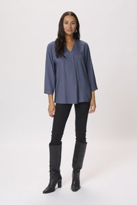 Blusa blu scuro con scollatura a V e maniche a tre quarti, caratterizzata da un motivo testurizzato. Abbinata a pantaloni slim-fit neri e stivali neri al ginocchio.