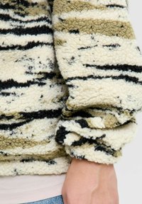 Fleece-Pullover mit einem wellenförmigen Muster in Schwarz, Oliv und Creme, gerippten Bündchen und einer weichen, strukturierten Oberfläche. Eignet sich für die Freizeit.