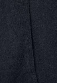 Mörkgrått tyg med en mjuk, strukturerad yta och lätt lyster. Materialet verkar elastiskt med en jämn och slät väv.