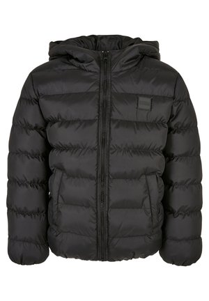 Enfant portant une veste matelassée noire à capuche avec zip et poches latérales, associée à un pantalon de jogging gris clair.