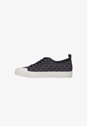 Black sneaker with a repeated circle pattern, rubber sole, white accents, lace-up design, and a rear pull tab for easy wear.