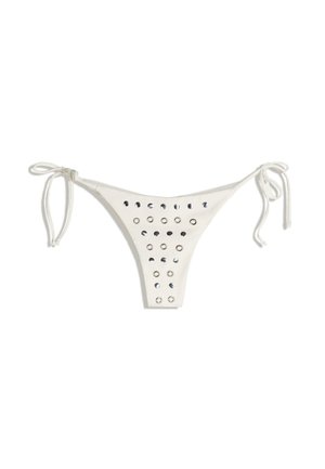 Slip de bikini alb cu legături subțiri pe părți, având un design decupat cu inele metalice circulare aranjate într-un model. Textură netedă.