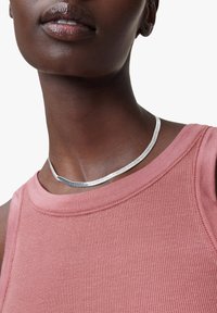 Collier en argent avec un design lisse et courbé porté par un modèle vêtu d'un haut rose à côtes. Le collier repose étroitement autour du cou.