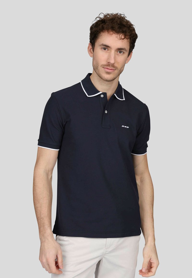 Polo marine en coton, avec un col classique à bord blanc, des manches courtes et un petit logo sur la poitrine gauche.