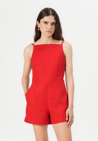 Romper rosso senza maniche in tessuto testurizzato, con scollo a quadrato e tasche laterali, tagliato all'altezza della coscia.