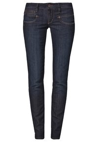 Vaqueros ajustados en denim azul oscuro. Incluye características como una cintura de altura media, bolsillos frontales y costuras en contraste. Textura suave con un mínimo desgaste.