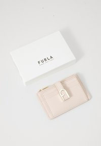 Furla kaarditasku heledast roosast nahast, millel on kuldsed riistad, mitmed kaarditaskud ja tõmbluku sektsioon. Valge karp kaasas.