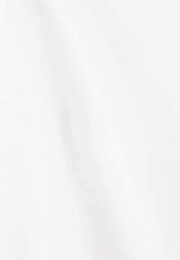 Λευκό ύφασμα με κοντινή λήψη μιας ραφής, που δείχνει την υφή και τη λεπτομέρεια των ραφών σε μια λεία επιφάνεια