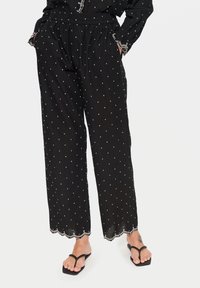 Svartmönstrade byxor med vita prickar, med elastisk midja, sidfickor och scalloped nederkant. Mjukt, lättviktigt tyg.