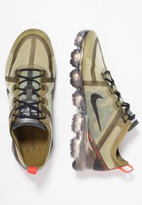 Scarpe Nike Air Max Vapormax in mesh verde, con suola traslucida, dettagli neri e particolari rossi sul tallone.
