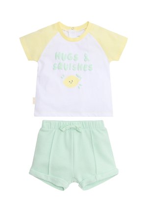 Camiseta de manga corta para niño pequeño con mangas amarillas y texto "Abrazos y achuchones" sobre un limón sonriente, combinada con pantalones cortos de cintura elástica color verde menta.