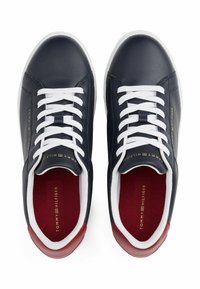 Marineblaue Ledersneaker mit weißen Schnürsenkeln, roten Akzenten und einem gepolsterten Kragen. Mit goldenem Branding an der Seite und einem kontrastierenden Innenraum.