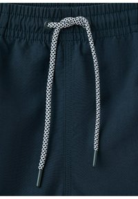 Ceinture élastique bleu marine avec cordon de serrage à motifs noirs et blancs noué en un nœud.