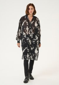 Schwarz-weiß gemustertes Longsleeve-Hemdkleid aus transparentem Stoff mit Knopfleiste, ergänzt durch einen klassischen Kragen und Manschetten.
