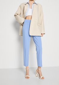 Cream linen oversized blazer, light blue tailored pants, and beige strappy heels. Textured fabric, structured fit, mid-rise waist.