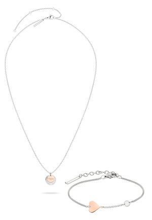 Collier chaîne en argent avec un pendentif rond en or rose et un bracelet en argent assorti avec un charm en forme de cœur en or rose.
