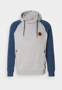 Sudadera gris con mangas de ranglán azules, capucha y cordones. Presenta un emblema marrón y triángulos de acento marrón en los lados.