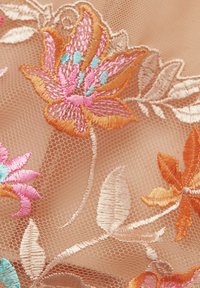 Geborduurd gaasstof met levendige bloempatronen in roze, oranje en blauw op een zachte, doorschijnende beige achtergrond.