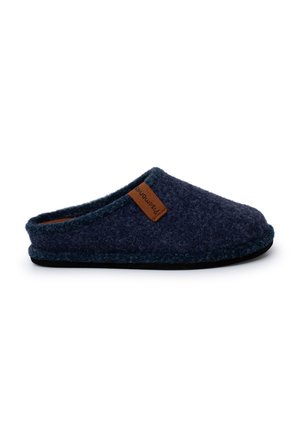 Chausson en feutre bleu marine avec une forme arrondie, présentant une étiquette en cuir beige et une semelle en caoutchouc noir pour une meilleure adhérence. Texture douce, utilisation intérieure.