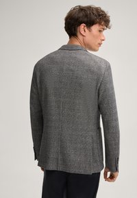 Grijze geruite blazer van gestructureerde stof, met smalle revers en twee achterventilaties. Bevat knoopmanchetten en heeft een getailleerde pasvorm.