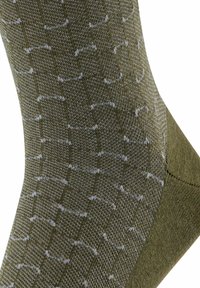 Calzini verdi a motivo con un design in maglia testurizzata e accenti bianchi a contrasto. La forma complessiva è standard, a lunghezza caviglia.