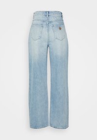 Calças largas de ganga azul claro, feitas de denim com um acabamento desbotado. Apresenta uma cintura alta, dois bolsos traseiros e um logótipo em pele.