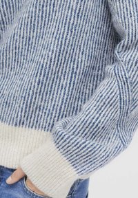 Sweter w paski w jasnoniebieskim i białym kolorze, o teksturowanym wzorze prążków i kremowymi mankietami. Miękki, przytulny materiał.