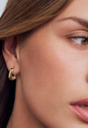 Guldfärgad ringörhänge med texturerad yta, med ett urtagsmönster och infattade små klara stenar för extra detalj.