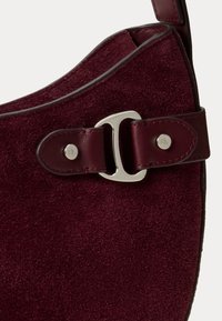Borsa in suede borgogna con bordi superiori curvi, dotata di una fibbia e di accessori in rivetti argentati per la chiusura e i dettagli. Finitura interna liscia.