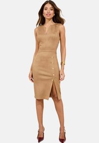 Fitted, sleeveless dress in soft, tan suede with a deep V-neck, side slit, and golden button accents along the front for detail.