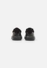 Sneaker neri con una combinazione di pelle liscia e suede, punta tonda e suola in gomma nera testurizzata con accenti minimi.