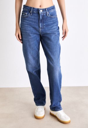 Blå denimjeans med avslappet passform, høy midje, femlomme-design og synlig søm. Stylet med hvite sneakers.