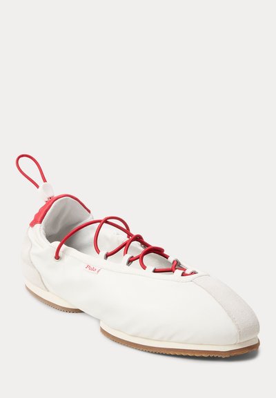 Witte en rode laagprofiel vrijetijdsschoen met rode elastische veters, suède neuskap, hieltreklus en rubberen zool met "Polo"-label aan de zijkant.