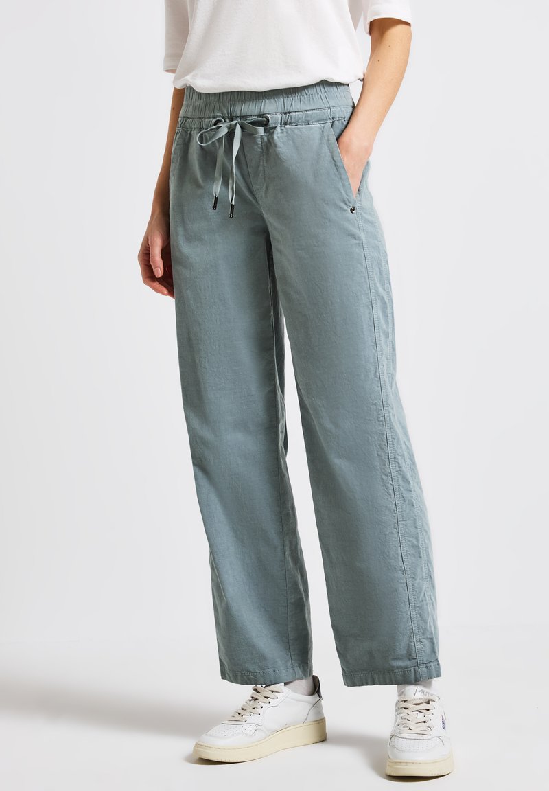 Pantalons bleu clair, amples, fabriqués en tissu doux. Comprend une taille élastique avec cordon de serrage, des poches latérales et des ourlets resserrés.