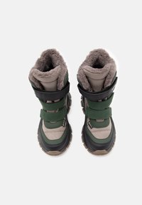 Zielono-czarne wodoodporne buty z puszystym szarym wyściółką, dwoma regulowanymi paskami, teksturowanym wierzchem i solidnymi brązowymi podeszwami zapewniającymi przyczepność.