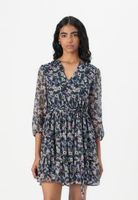 Rochie florală cu un fundal întunecat, prezentând un decolteu în V, mâneci trei sferturi, talie strânsă și fustă cu straturi. Fabricată dintr-un material ușor și transparent.