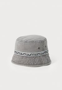 Grå denimbøttehatt med teksturert skygge, med et dekorativt bånd i svart og lyseblå mønstre og ventilasjonshull på siden.