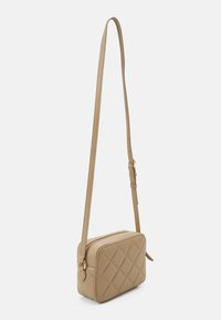 Quilted beige crossbody bag made of soft material, featuring a rectangular shape, adjustable strap, and gold hardware accents.