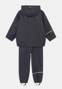 Vattentät tvådelad regnjacka i mörk marinblå, med en huva, elastiska ärmmuddar och matchande byxor med reflexstripes.