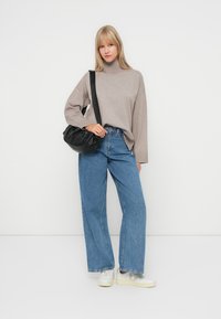 Oversized beige turtleneck sweater, light blue wide-leg jeans, and white sneakers. Accessorized with a black slouchy handbag.