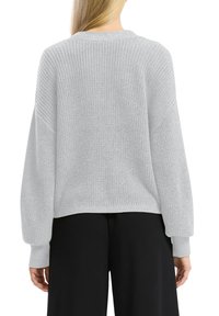 Šviesiai pilkas megztinis su laisvu siluetu, nukritusiais pečiais ir raukšlėtais manžetais, pavaizduotas iš nugaros prieš vienodą foną.