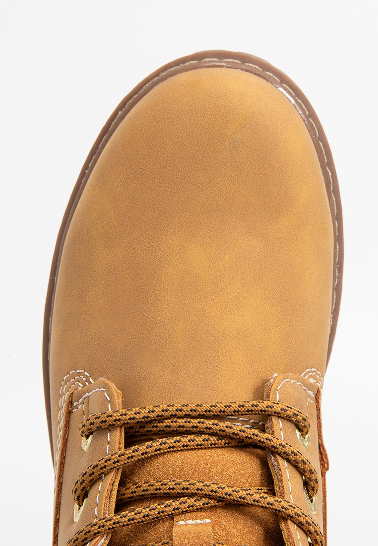 Botín de cuero marrón con puntera redonda, superficie texturizada, costuras reforzadas y cordones marrones. Presenta ojales de metal para mayor durabilidad.