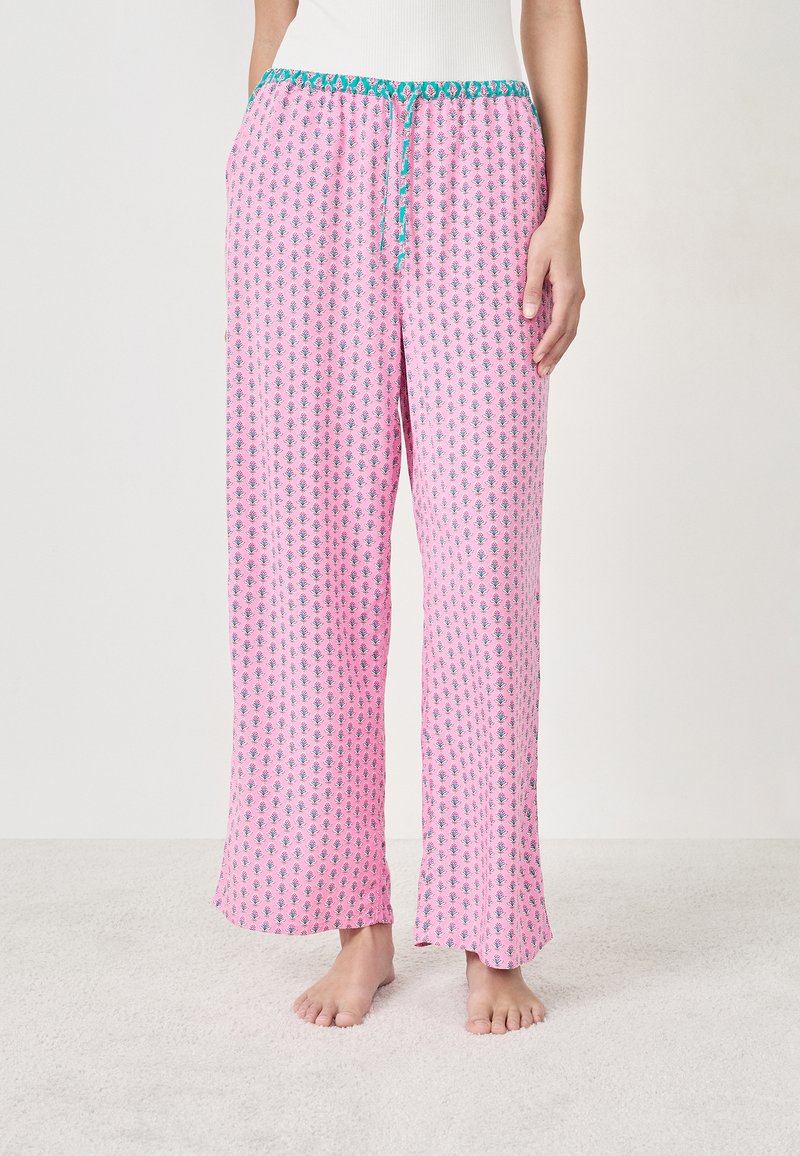 Różowe spodnie piżamowe z powtarzającym się wzorem graficznym, luźny krój, elastyczny pas z turkusowym sznureczkiem i miękka tekstura.