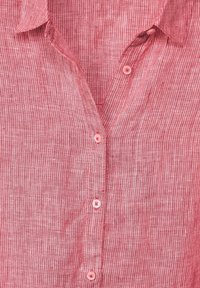 Camisa de cuadros rojos y blancos con cuello doblado, que presenta cuatro botones rosas visibles a lo largo de la tapeta frontal.