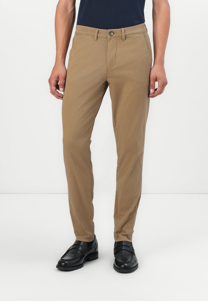 Tan chinos med slim fit, med frontlommer, knappelukking og en glatt, bomullstekstur. Båret med svarte dressko.