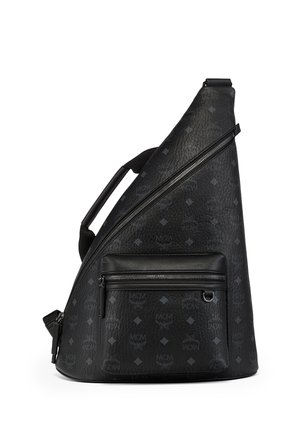 Czarny, teksturowany skórzany plecak typu sling z przednią kieszenią na zamek, ukośnym suwakiem oraz subtelnym wzorem logo MCM.
