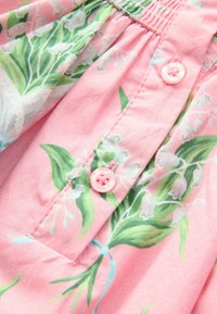 Rózsaszín virágmintás anyag zöld levelekkel. Ráncolt tetejű, középen rózsaszín gombdísszel, amely kiemeli a mintát.